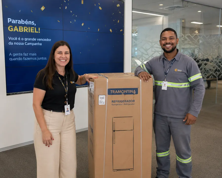 Colaborador da BMA ao lado da gestora e do refrigerador ganho na campanha interna